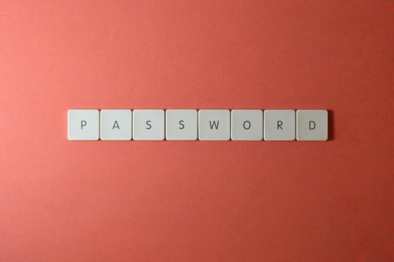 Focus on password security with white keyboard tiles spelling 'PASSWORD' on a coral background.