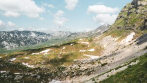 Scenic landscape of mountain ranges in Montenegro with patches of snow under a blue sky.