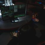 A group of people in a dark room working on computers, related to cybersecurity.