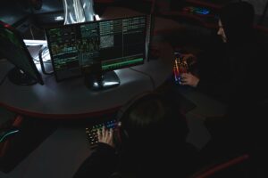 A group of people in a dark room working on computers, related to cybersecurity.