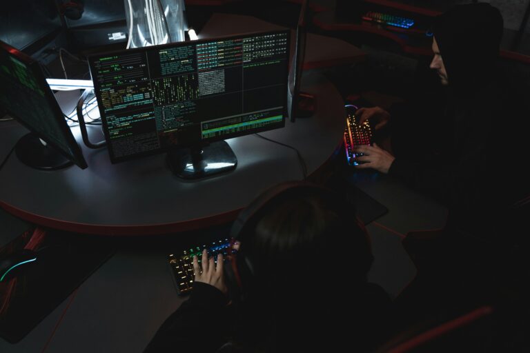 A group of people in a dark room working on computers, related to cybersecurity.