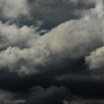 Moody and dramatic overcast cumulus clouds fill the sky, creating a captivating dark sky scene.
