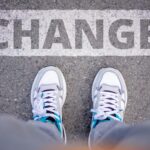 Close-up of sneakers on street with 'Change' text, symbolizing transformation.